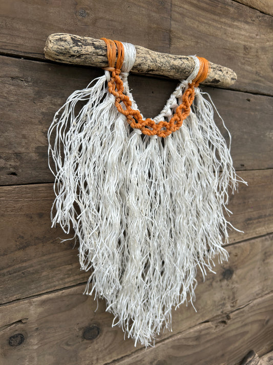 Side angle of coastal rope wall art created with retired fishing ropes with a weathered white fringe and sun-faded orange circles on driftwood.