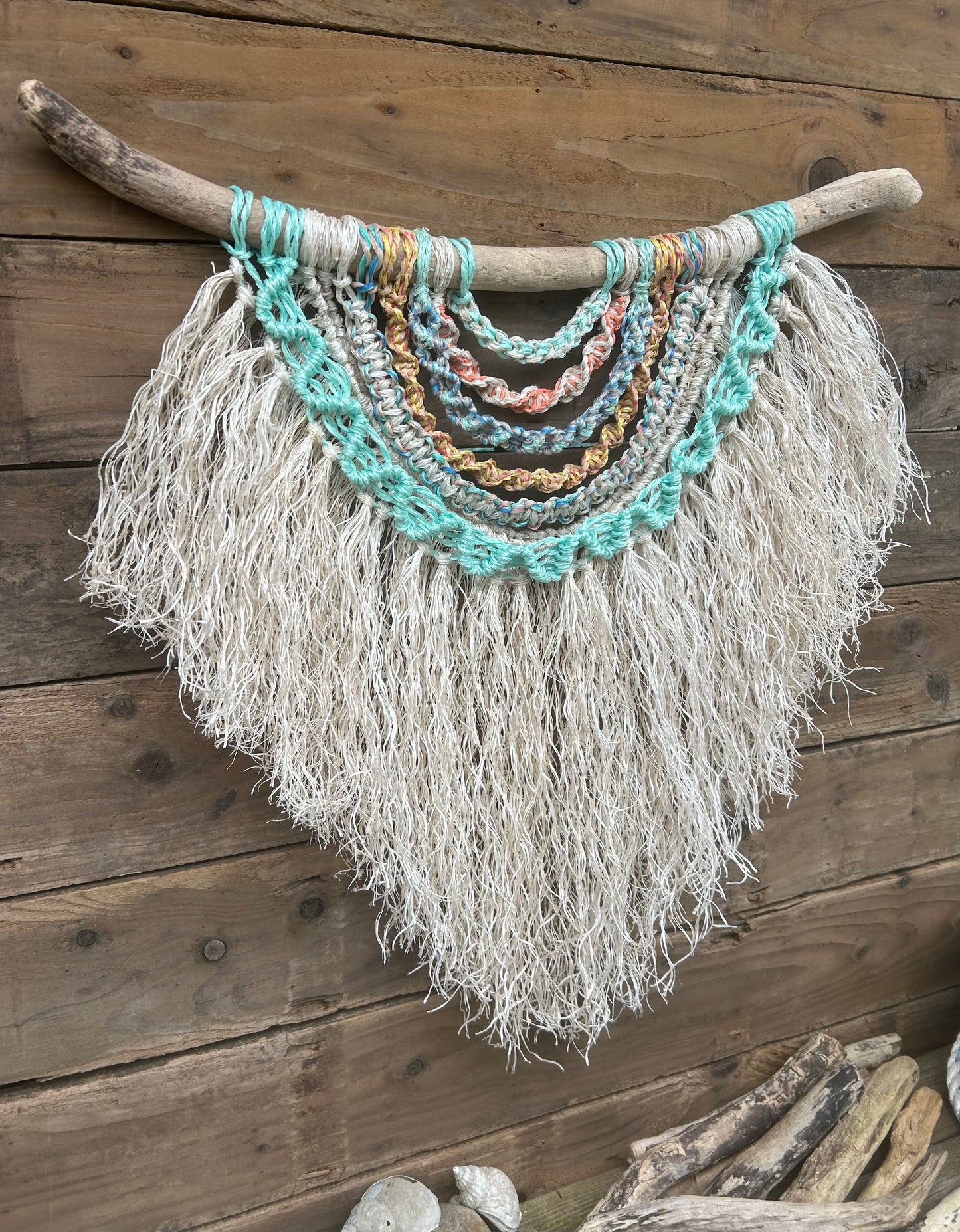Ocean inspired wall piece handmade from reclaimed fishing rope, in sun-washed colours and a soft white textured fringe on driftwood.