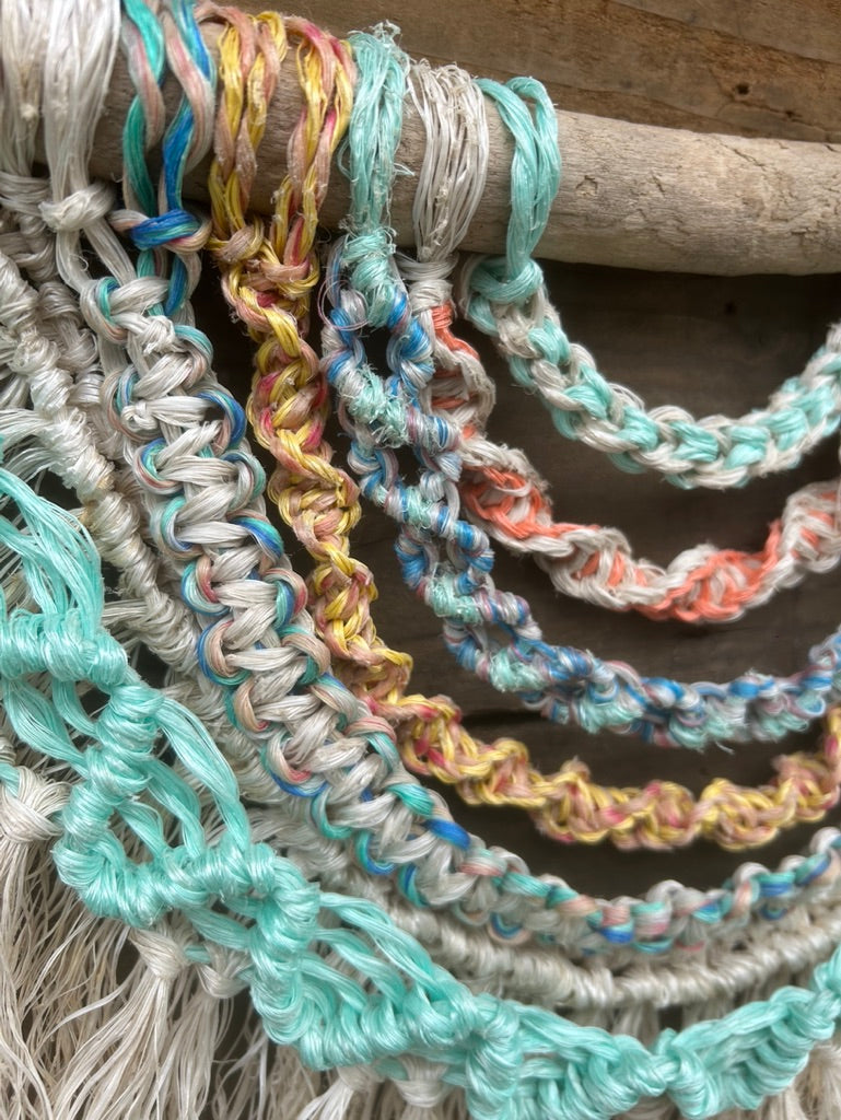 Close up shot of layered wall hanging, handmade from reclaimed marine ropes in soft coastal tones.