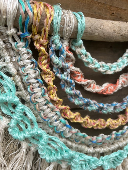 Close up shot of layered wall hanging, handmade from reclaimed marine ropes in soft coastal tones.