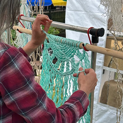 Close-up photo of hand knotting a sea green half mandala with repurposed fishing rope at Croyde Village Sunday Market.