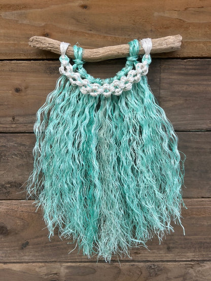 Ocean inspired coastal wall hanging handcrafted from repurposed fishing rope, with a sea-green fringe and band of weathered white flower knots.