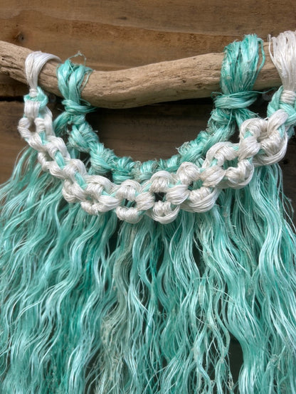 Close up shot of coastal rope macramé wall art handmade from retired fishing rope with sea-glass green fringe and weathered white flower knots.