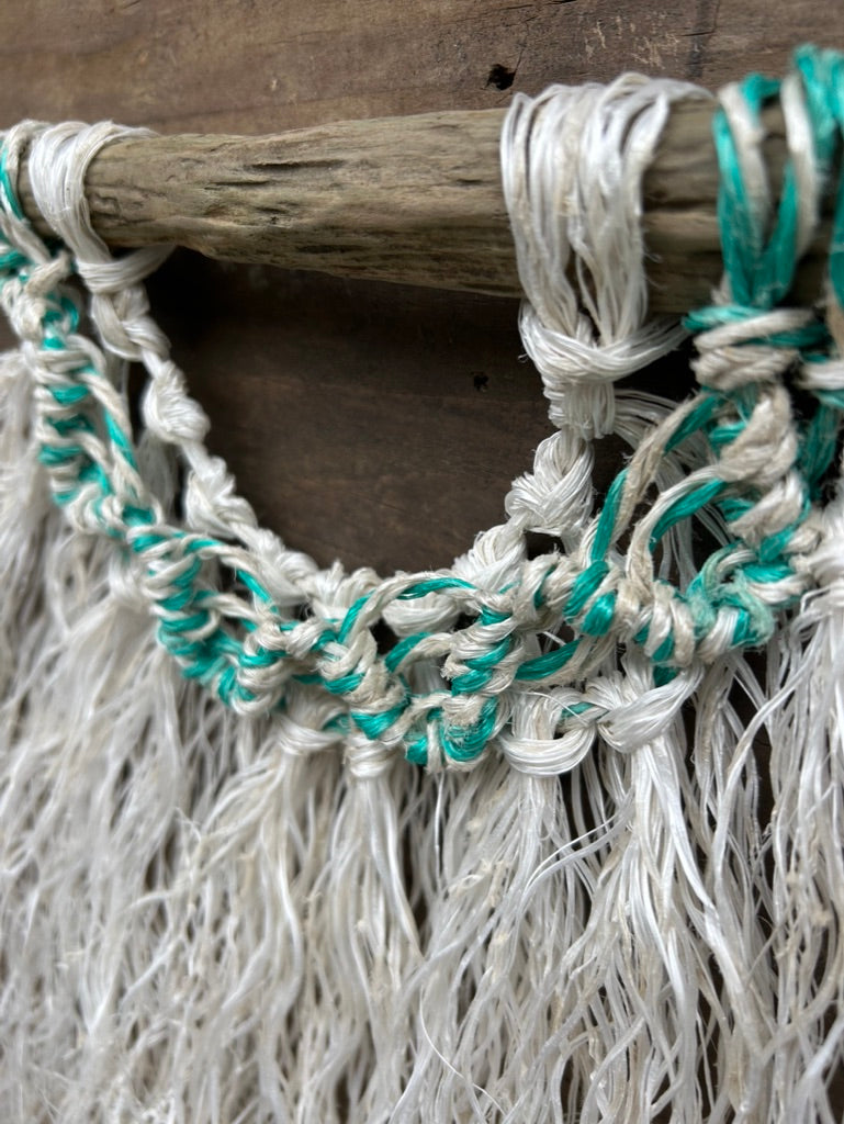 Close-up of a sea-green and white wave, hand-knotted from repurposed fishing ropes and transformed into coastal wall art.