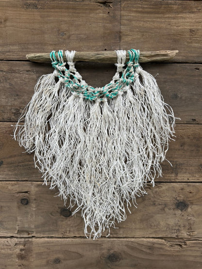 Repurposed fishing ropes are transformed into unique, sustainable nautical rope wall art, featuring a weathered white fringe and sea-green and white wave on driftwood.