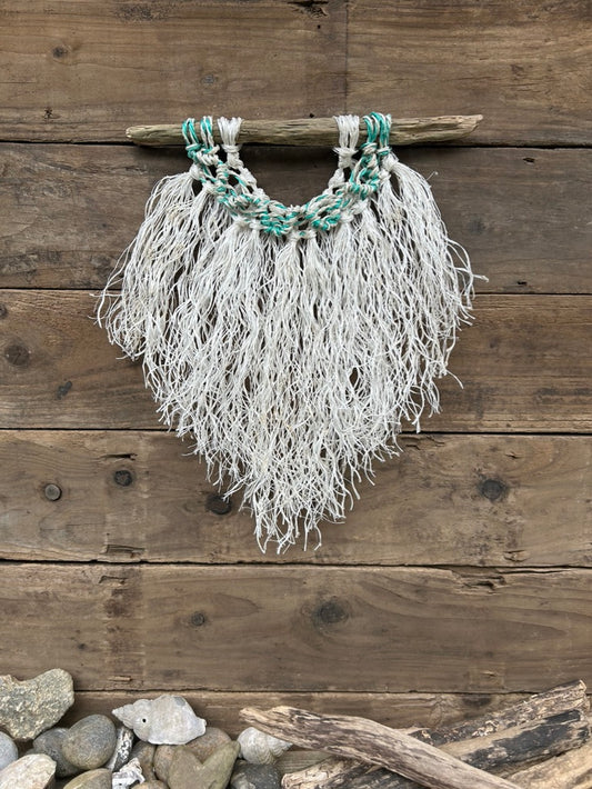 Weathered white coastal wall hanging hand-knotted from reclaimed fishing ropes featuring a sea-green and white wave on driftwood.