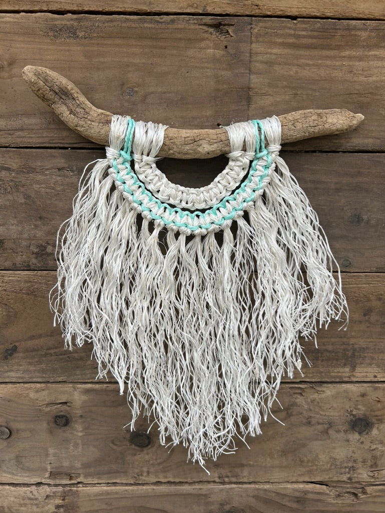 Sustainable, ocean inspired coastal decor, handcrafted from retired fishing ropes. With a weathered white fringe and a soft green current detail, set on driftwood.
