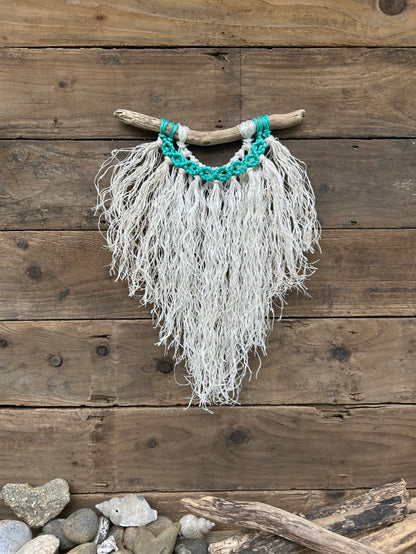 Coastal wall hanging handmade from repurposed fishing ropes with a weathered white fringe and vibrant, sea-green circles on driftwood.