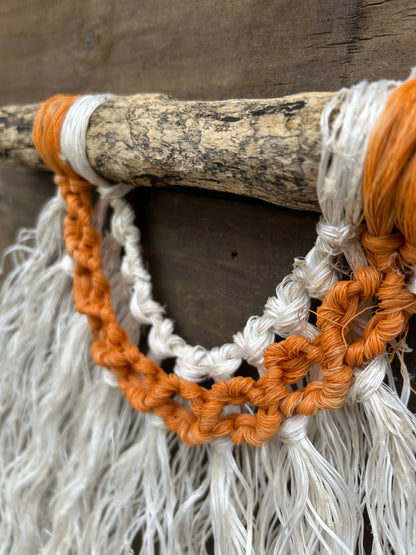 Close up of sun-faded orange circle knots made from repurposing reclaimed fishing ropes and transforming them into handmade coastal wall art.