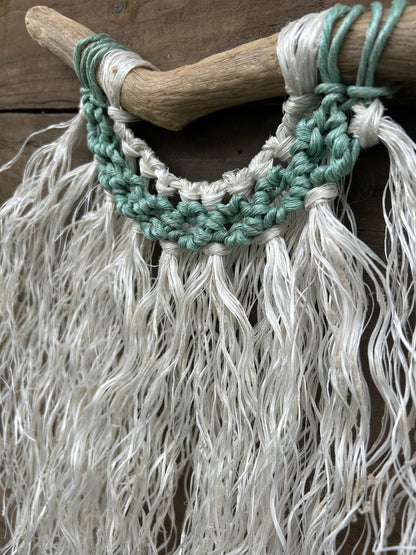 Close-up of a sustainable ocean inspired wall hanging with a weathered white fringe and sea-foam circles handcrafted from retired fishing ropes.