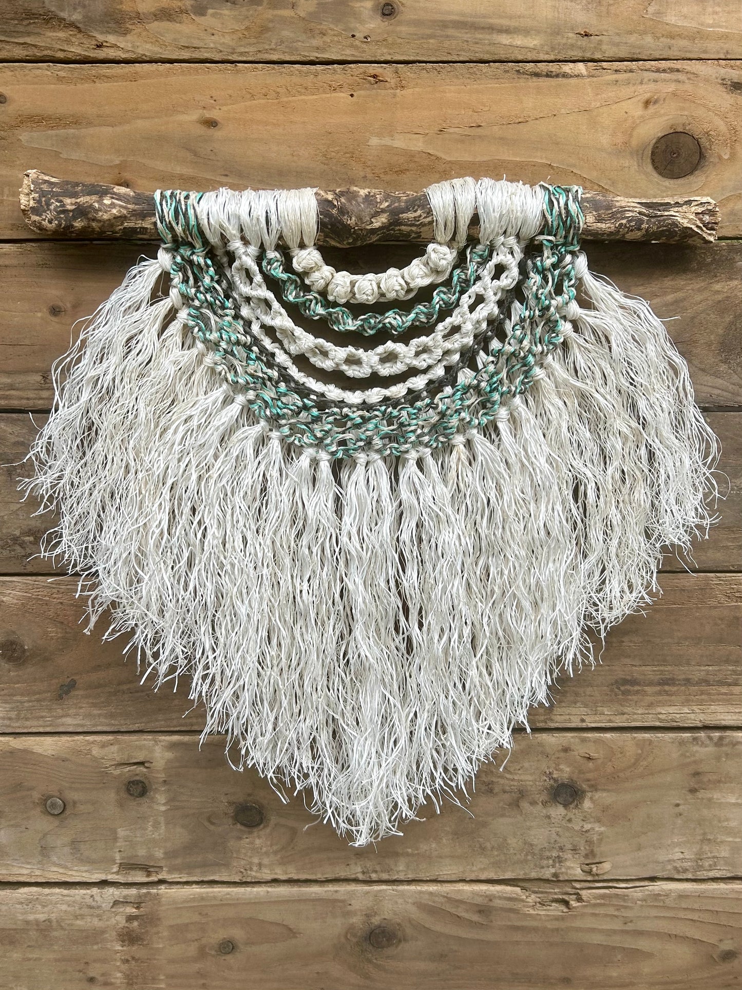 Sustainable, eco-friendly wall art created from retired fishing ropes, with a weathered white fringe and coastal tidal tones of green and black.
