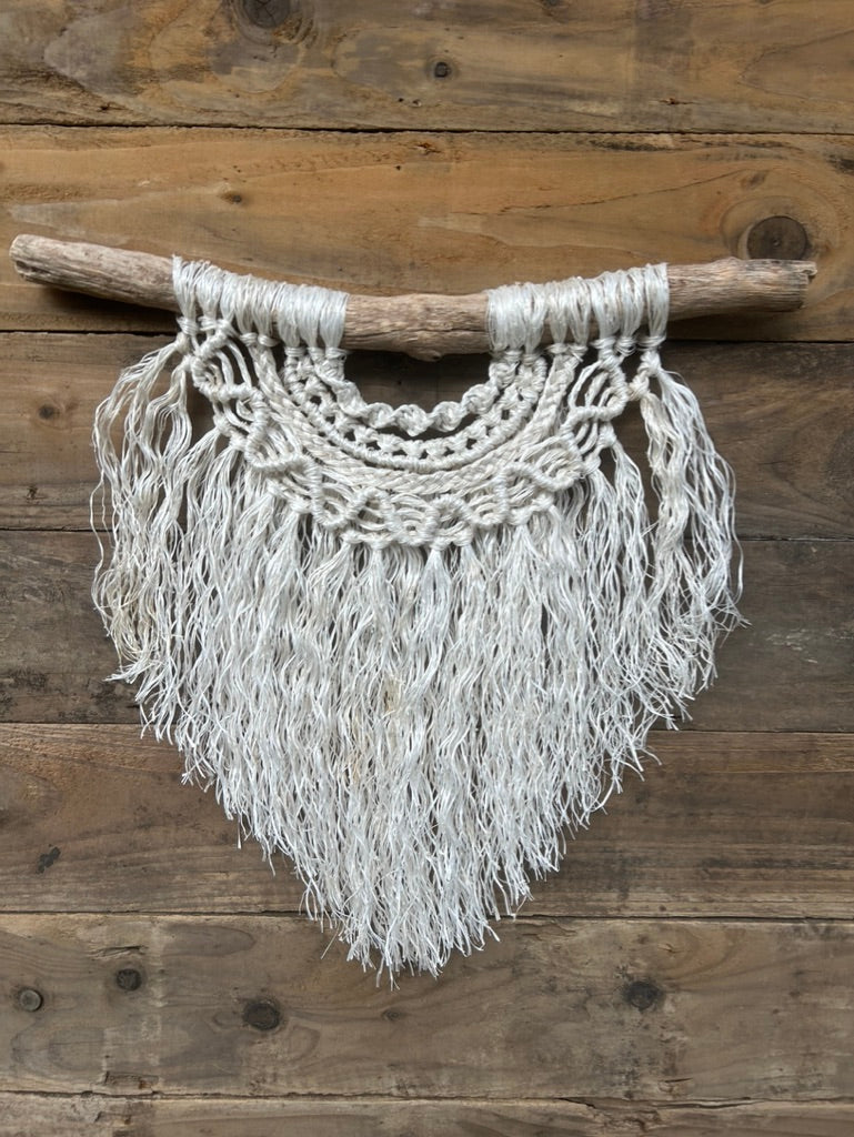 Handmade, layered rope wall art crafted from repurposed rope with textured knots, a sustainable coastal piece in soft white, set on driftwood.