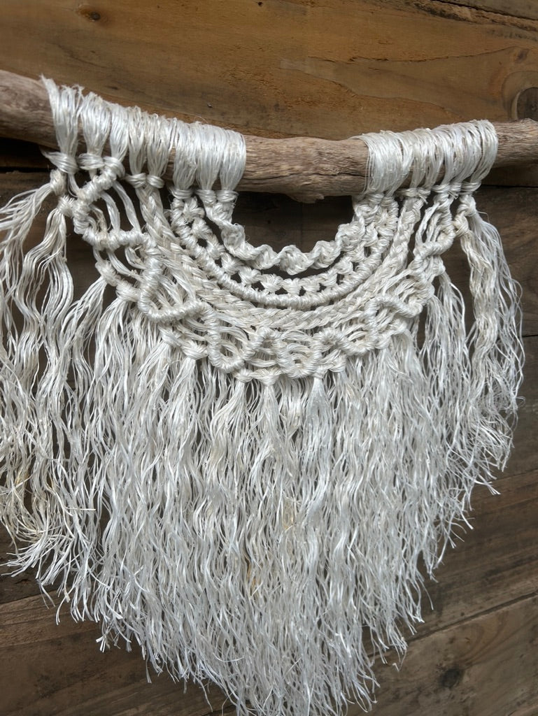 Side shot of sustainable coastal wall hanging in soft, weathered white on driftwood, highlighting wave detail and texture.