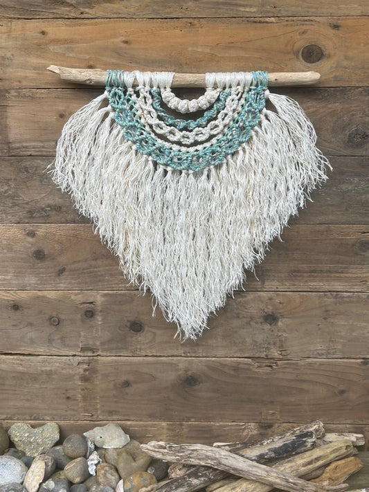 Textured, multi-layered wall art, handmade from repurposed fishing ropes, in weathered white and coastal sea green and sea blue tones, set on driftwood.