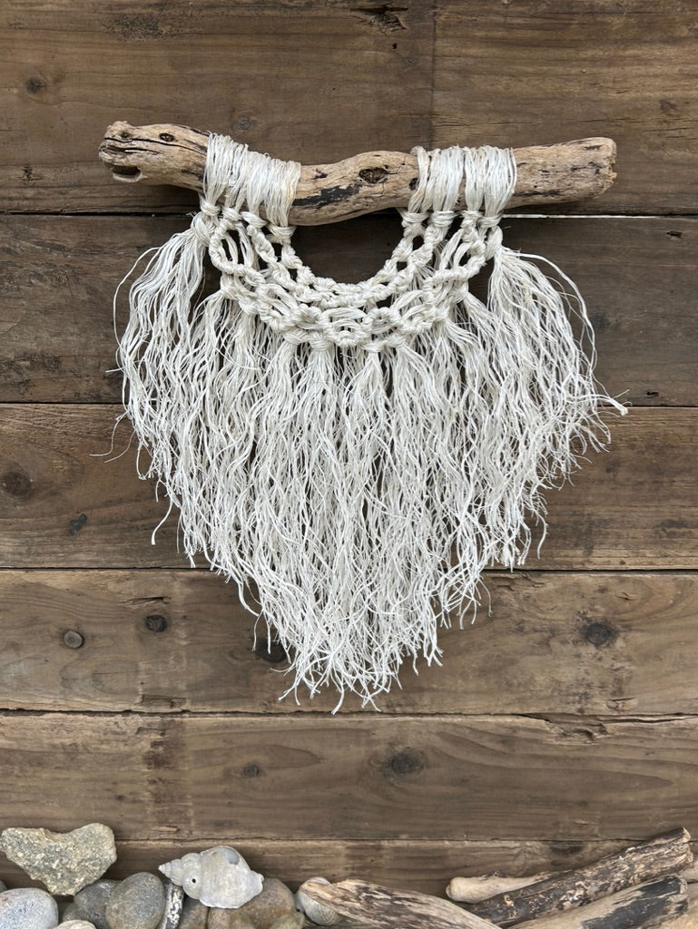 Three layered coastal boho wall art, handcrafted sustainably from recycled fishing rope, with a weathered white fringe and wave knots, set on driftwood.