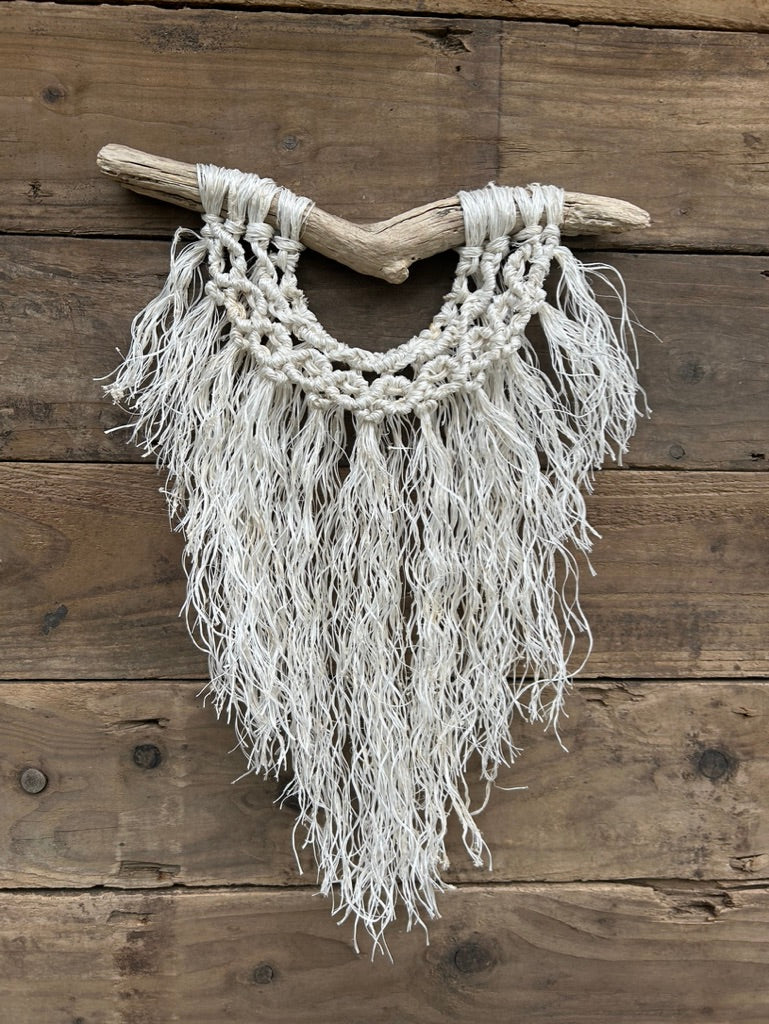 Sustainable coastal interior wall art, from recycled fishing rope that has been reworked by hand, with a soft white fringe and band of circle knots, set on driftwood.