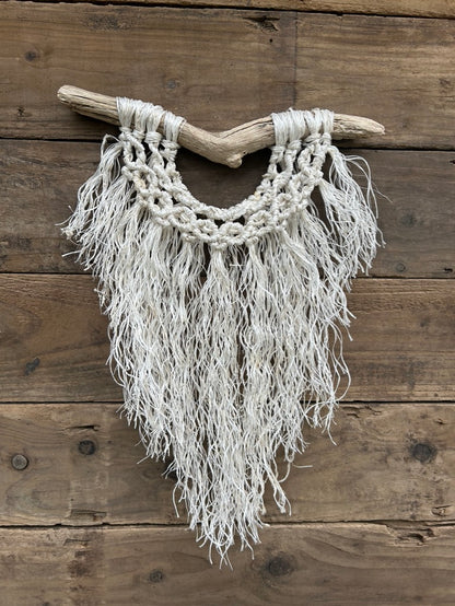 Sustainable coastal interior wall art, from recycled fishing rope that has been reworked by hand, with a soft white fringe and band of circle knots, set on driftwood.